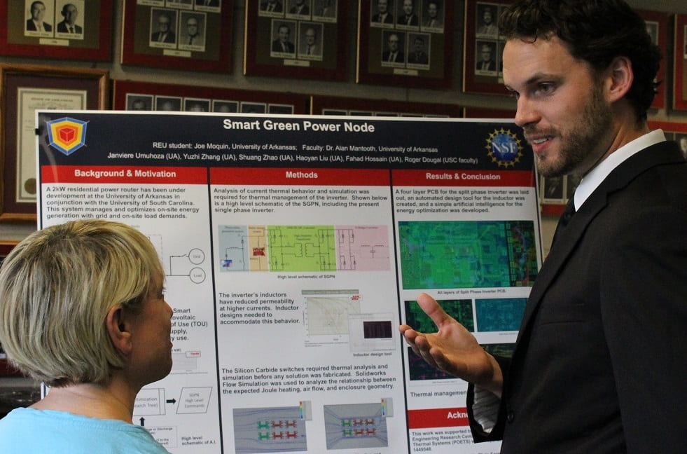 Picture of student explaining his poster to someone. 